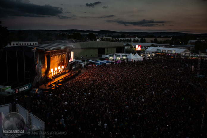 M’era Luna 2024 – Running Order steht, hier downloaden Überblick über das M'era Luna Festival 2018, Bühne und Festivalgelände sind im Sonnenuntergang bereits dunkel. Auf der Bühne spielen In Extremo, Flammensäulen steigen auf.
