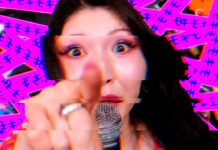 Otoboke Beaver veröffentlichen neues Album Singer pointing directly at the camera while singing into a microphone, with a bright pink glitchy background behind her.