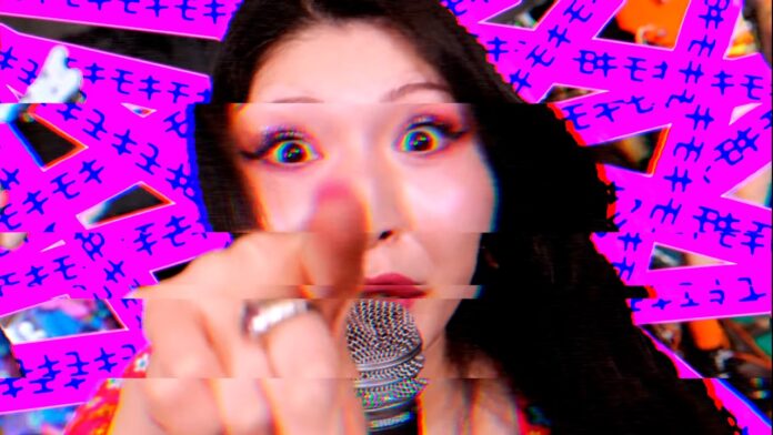 Otoboke Beaver veröffentlichen neues Album Singer pointing directly at the camera while singing into a microphone, with a bright pink glitchy background behind her.