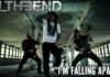 Four-member metal band performing in a derelict concrete space; vocalist center with mic, two guitarists flanking him, drummer in back; text overlays read 'TIL THE END' and 'I'M FALLING APART'