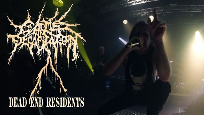 Cattle Decapitation präsentieren Video zu „Dead End Residents“; kündigen neue Albumpläne an Live metal concert: vocalist kneels on stage with microphone, band logo and bright stage lights behind him.