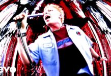 The Offspring veröffentlichen 4″-Single von „Pretty Fly“ Male singer with blonde hair performs into a microphone on a vibrant, swirling red-and-white concert backdrop (Verve logo visible).