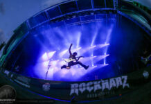 Rockharz Open Air 2026 Guitarist mid-air jump on a lit stage at Rockharz festival with blue/purple lights.