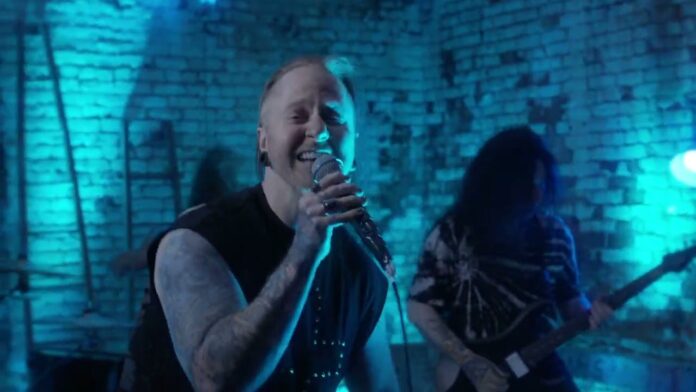 A Skylit Drive unterschreiben bei Vaux Records und veröffentlichen das Musikvideo zu „Half Hearted“ Male vocalist sings into a microphone on a blue-lit brick-walled stage; guitarist in the background with tattoos visible on his arms.