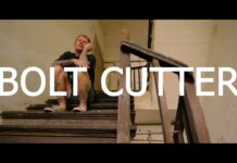 Evergreen Terrace veröffentlichen nächsten Monat eine Coverversion von Jimmy Eat Worlds „Bleed American“ Thumbnail for a video titled 'BOLT CUTTER' showing a man seated on a dusty, decayed staircase in an abandoned building with graffiti in the background.