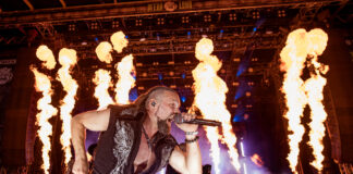 Das war das M’era Luna 2026 Male rock singer on a fiery stage, holding a microphone and mid-performance with pyrotechnics behind him.