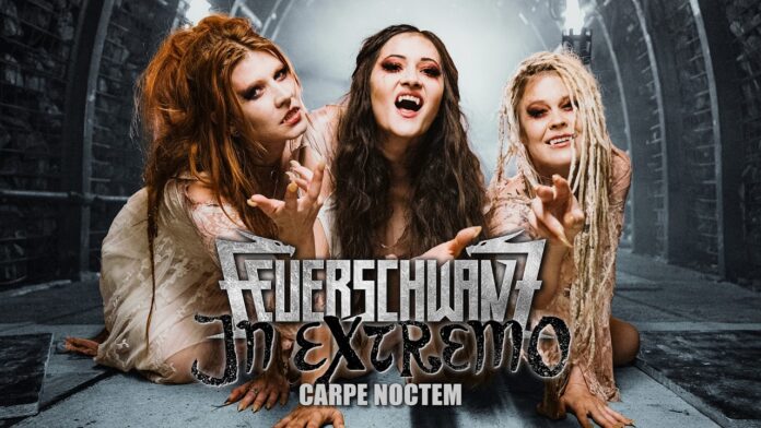 Feuerschwanz und In Extremo veröffentlichen „Carpe Noctem“ Three women with dramatic makeup pose on a stage-like set, front and center, with a bold band logo and 'Carpe Noctem' text beneath them.